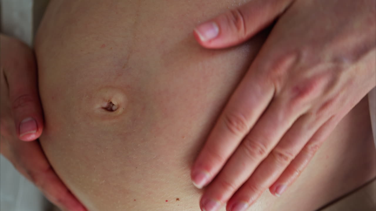 Primo piano di una donna che si massaggia la pancia con l'olio durante la gravidanza