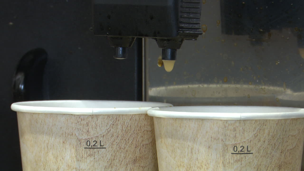 Coffee being dispensed into paper cups