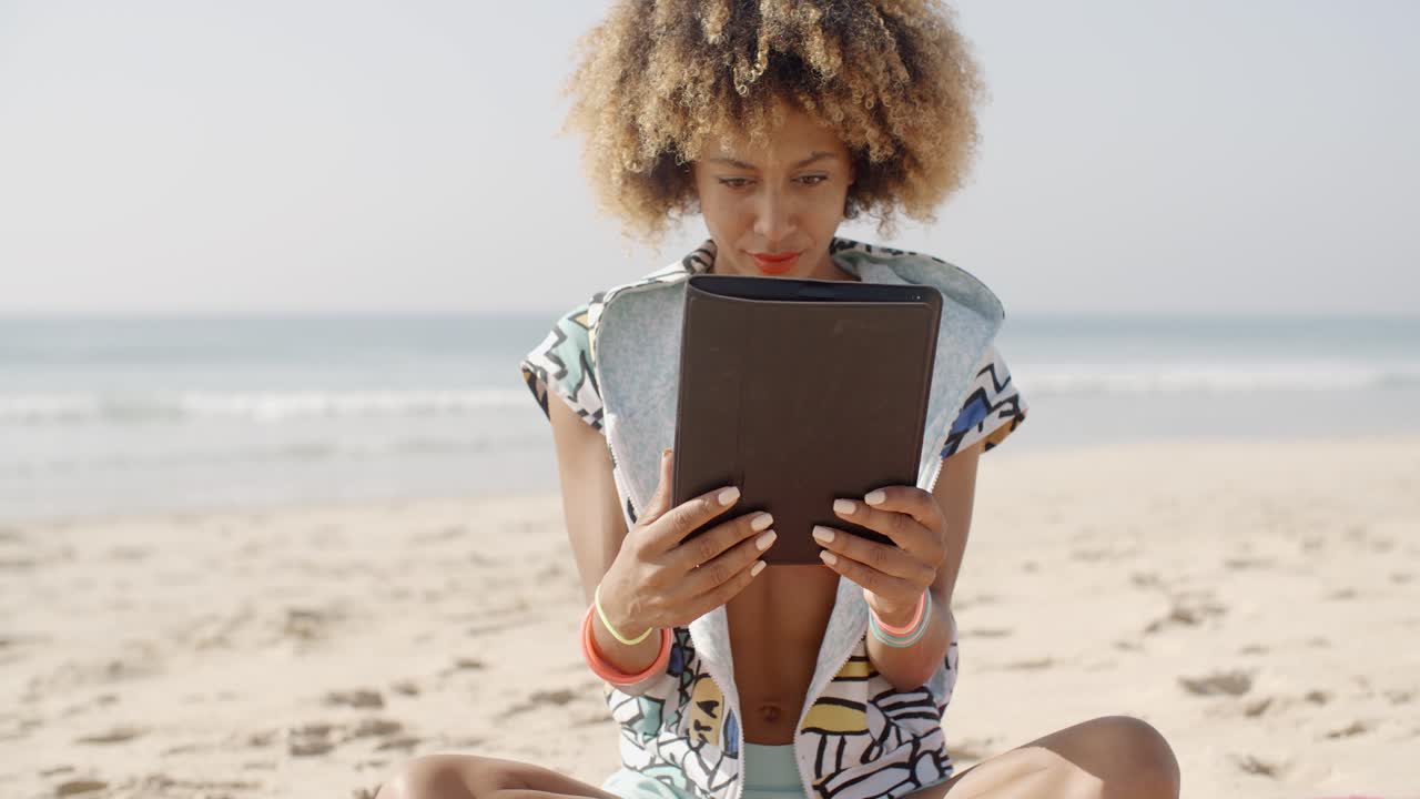 chica usando una tableta en la playa