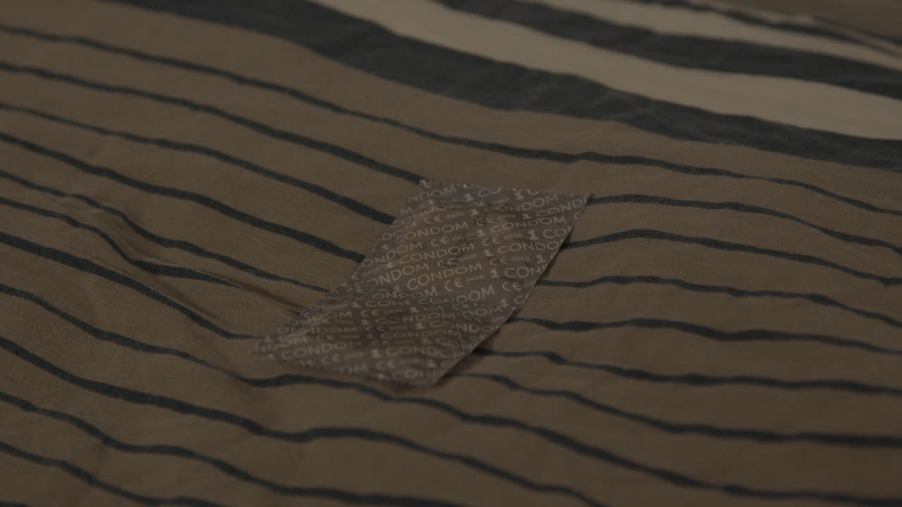 침대에 베개에 누워 래핑된 콘돔 쌍의 가까운 인형
