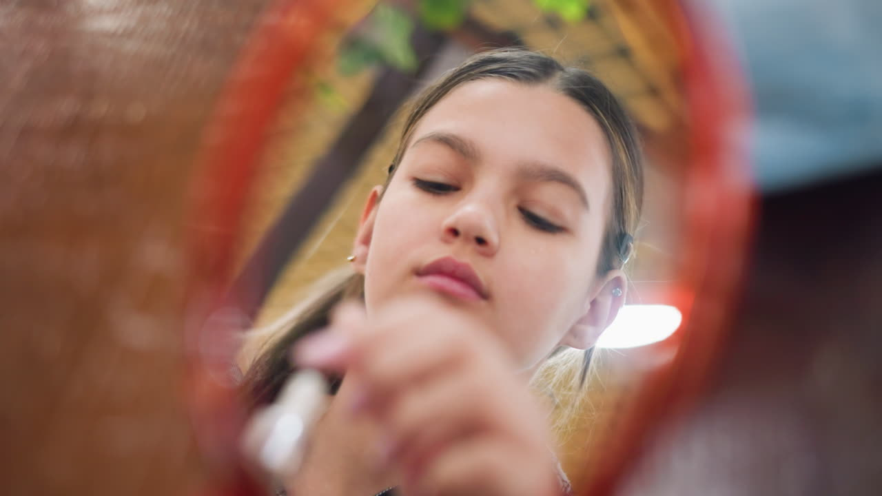 Closeup mirror reflection of young girl applying serum on face, gently rubbing skincare product for hydration and glow, soft lighting enhances beauty emphasizing self-care and skin nourishment