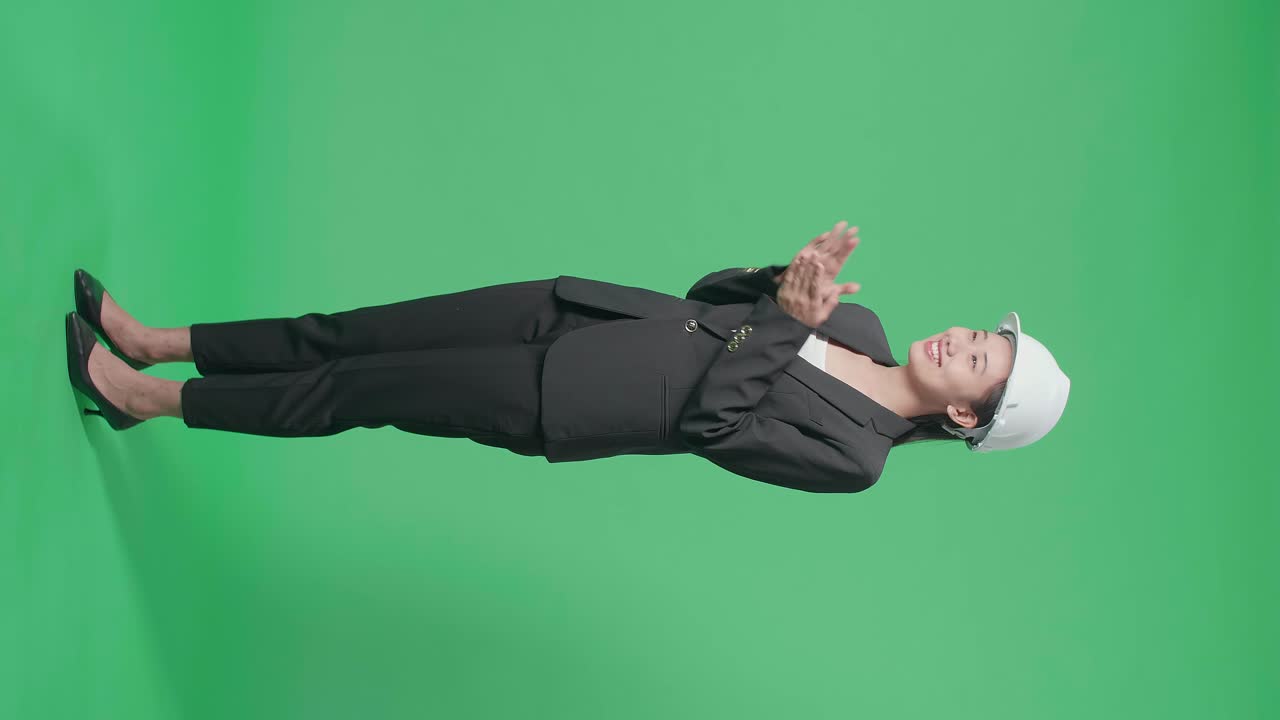 Full Body Side View Of Smiling Asian Female Engineer With Safety Helmet Clapping Her Hands In The Green Screen Studio