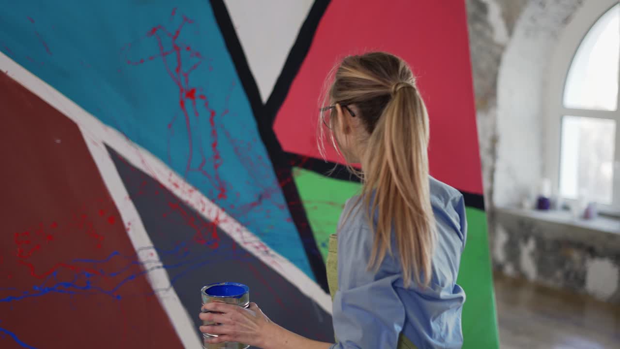artista femenina crea emocionalmente una obra maestra de pintura abstracta en el estudio frente a la ventana