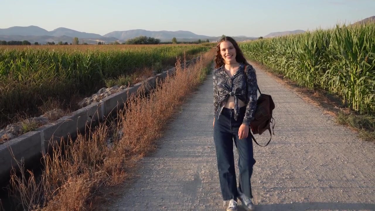 Una donna cammina con grazia su un sentiero panoramico, circondata dalla bellezza della natura.