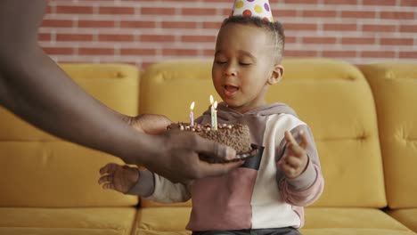 father gives birthday's cake for his son keep his eyes closed