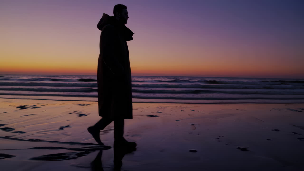 Hombre caminando por la playa al atardecer