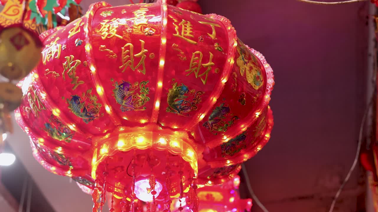 Red Chinese lantern spins, glowing warmly in Bangkok’s Chinatown at night