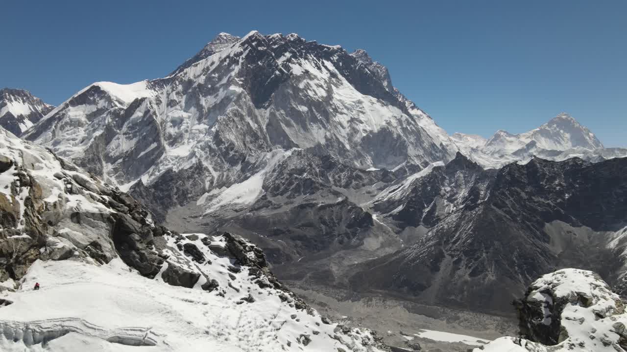 Drone view of Makalu Base Camp in Nepal showing rugged snow-covered peaks, rocky slopes, and glaciers under a clear blue sky, capturing the dramatic beauty of the eastern Himalayas