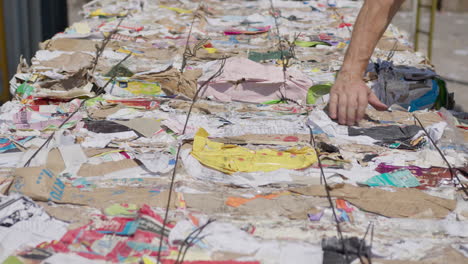 male hand inspects large bale of paper at recycling facility, static