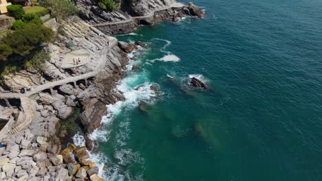 rocky coastline with turquoise water, path winding along cliffs in italy, aerial view