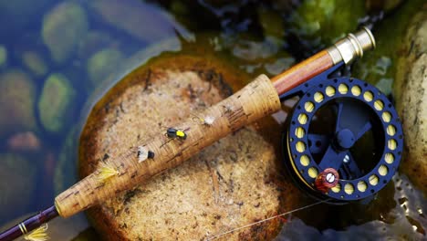 Fly-fishing-rod,-reel-and-hook-on-rock