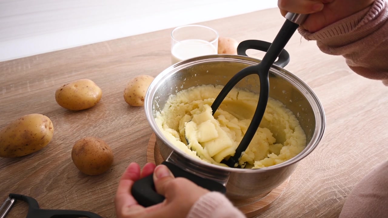 Preparazione di purè di patate schiacciando patate bollite.