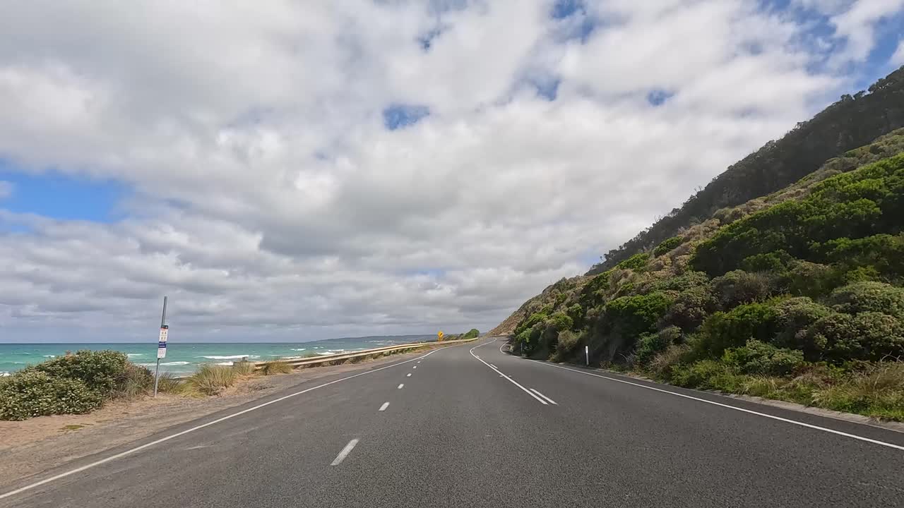 A 14-second drive showcasing coastal views, winding roads, and lush greenery under a partly cloudy sky