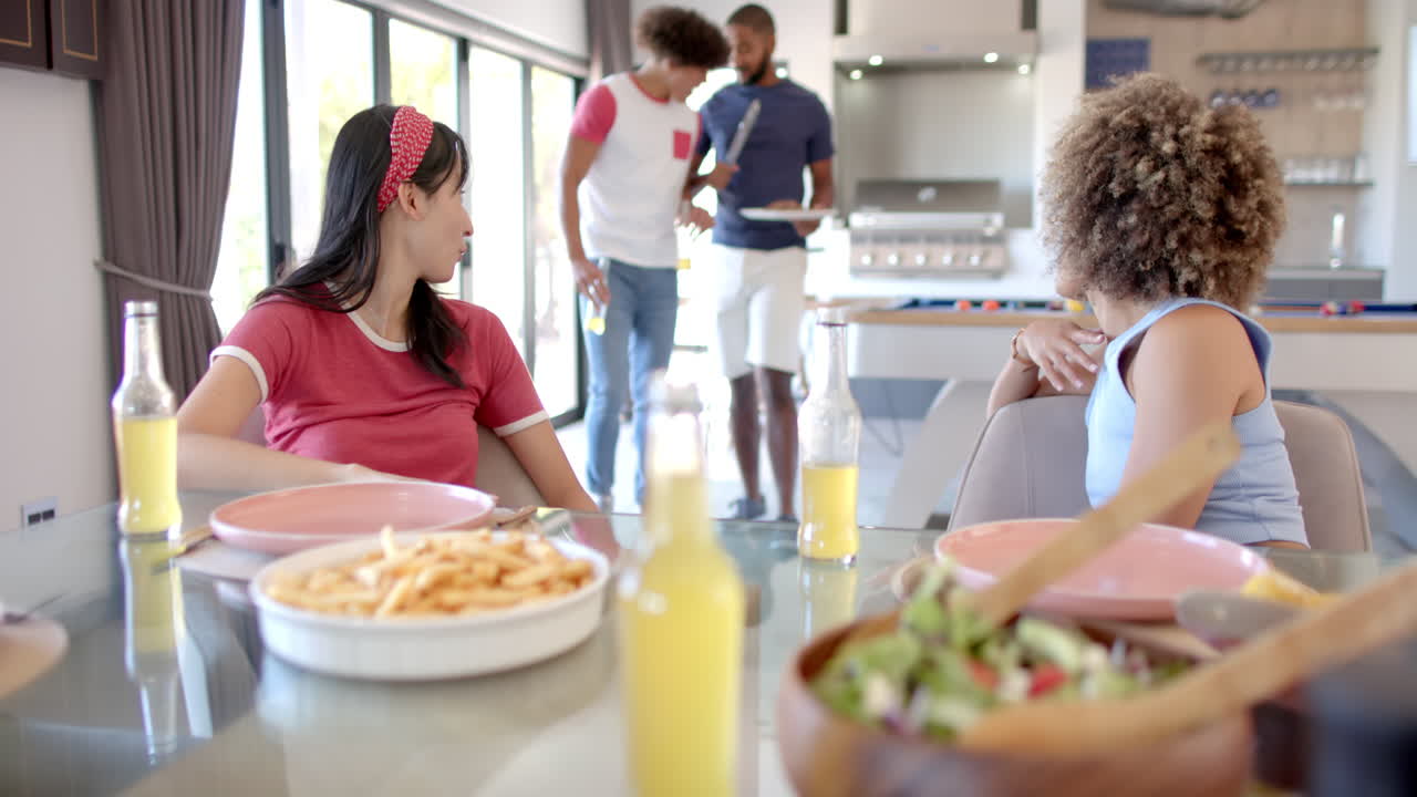 Enjoying lunch, Diverse friends sitting at table with drinks and food, socializing together