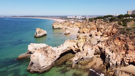vista aérea de drones de la playa praia dos tres irmaos en algarve, sur de portugal - hermosa costa con acantilados rocosos, turistas, hoteles y mar azul claro