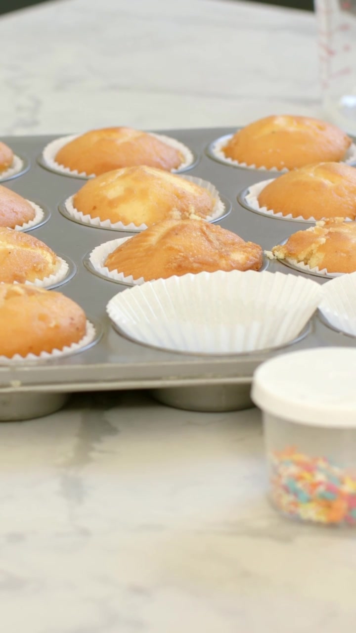 Vertical video: Shifting camera from blur revealing muffin pan on kitchen counter to show sprinkles