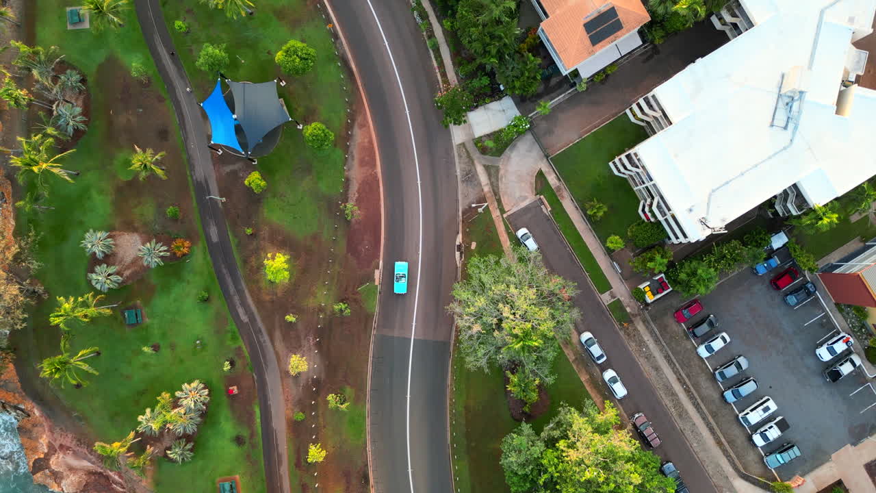 해안선을 따라 긴 구불구불한 길을 따라 푸른 청록색 복고풍 자동차의 드론 공중