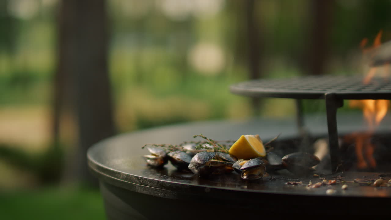 Un ragazzo sconosciuto che prende frutti di mare dalla griglia. Mani di un uomo che raccolgono cozze dalla griglia