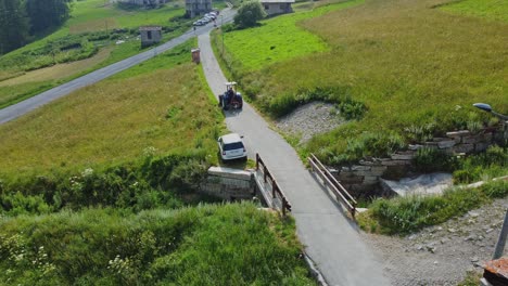 Toma-Aérea-De-Seguimiento-De-Un-Tractor-En-Una-Carretera-Desolada-En-La-Región-Rural-De-Los-Alpes-Cotianos,-En-La-Frontera-Entre-Italia-Y-Francia.