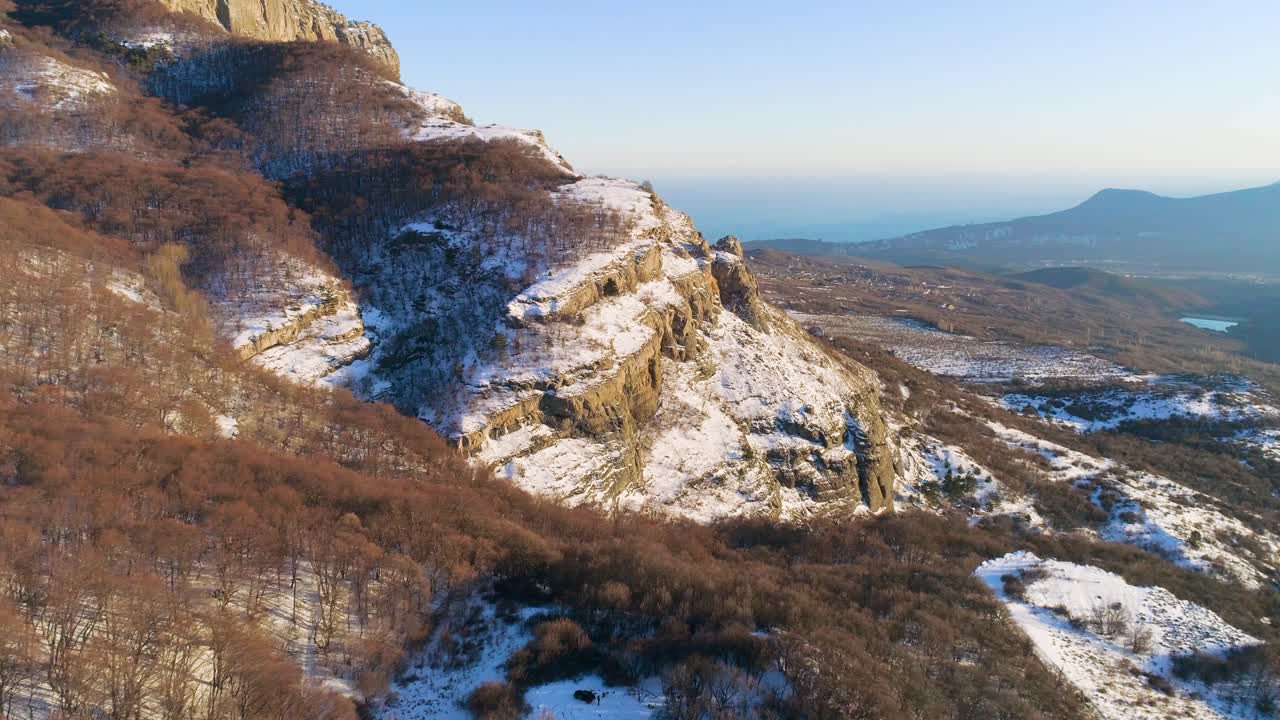 paisaje montañoso nevado con bosque y acantilado