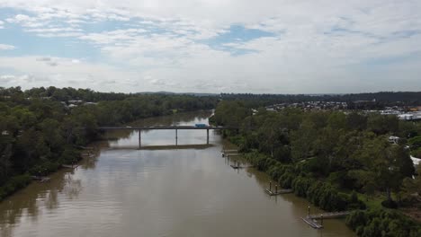 vista aérea de un río marrón y volando hacia un puente