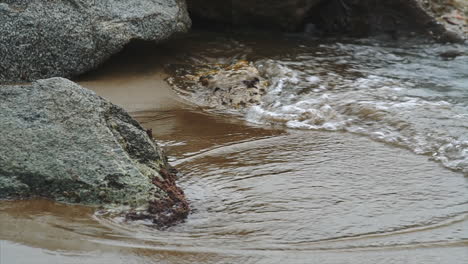 slow motion of waves crashing on rocks with a sandy beach