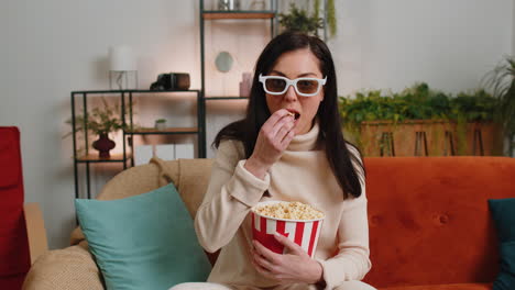 woman sitting on couch eating popcorn and watching interesting tv serial sport game online at home