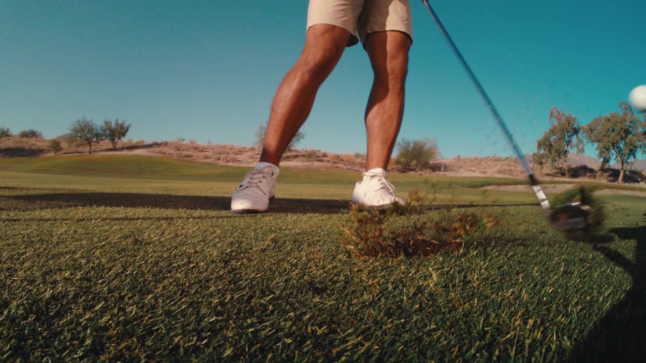 Un golfista colpisce la palla creando una zolla perfetta nel fairway. Primo piano grandangolare in avvicinamento di un golfista di alto livello, ripresa di golf in slow motion estremo di lato con terra che vola in una giornata di sole, in 4k a 800 fps.