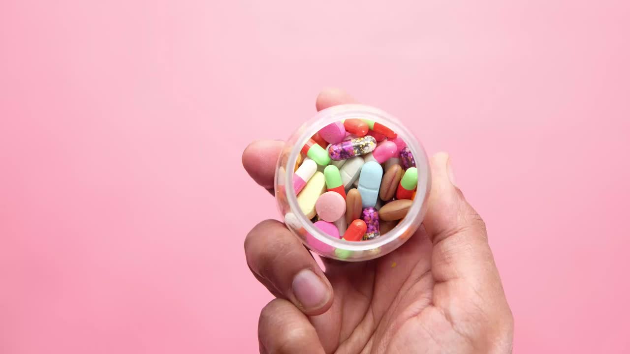 mano sosteniendo un recipiente de pastillas variadas