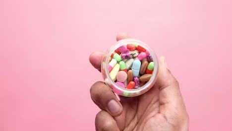 mano sosteniendo un recipiente de pastillas variadas