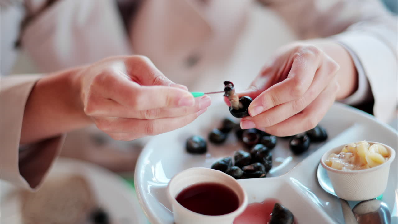 Close up of a woman eating snails at a restaurant