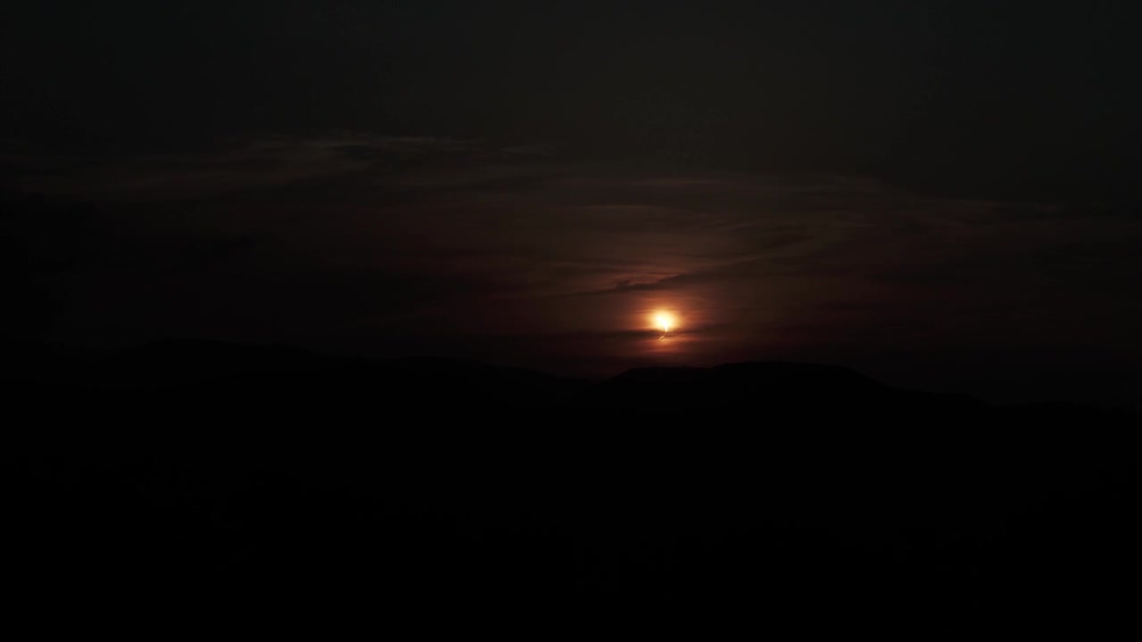 Cielo oscurecido mientras el sol está parcialmente oculto durante un eclipse solar sobre colinas