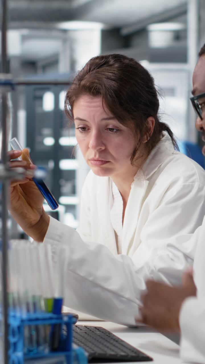 Vertical video Team of lab researchers inspecting chemical solutions in glass flasks