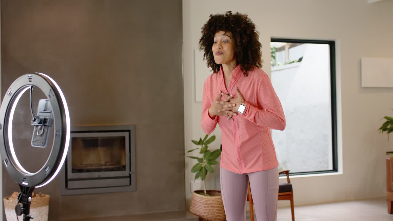 Una donna afroamericana registra un video da casa, salutando il pubblico, utilizzando una ring light e ponendo l'accento sulla salute.