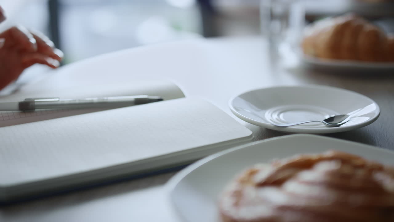 카페에서 앉아있는 커피 휴식 시간에 비즈니스 메모를 쓰는 여성.