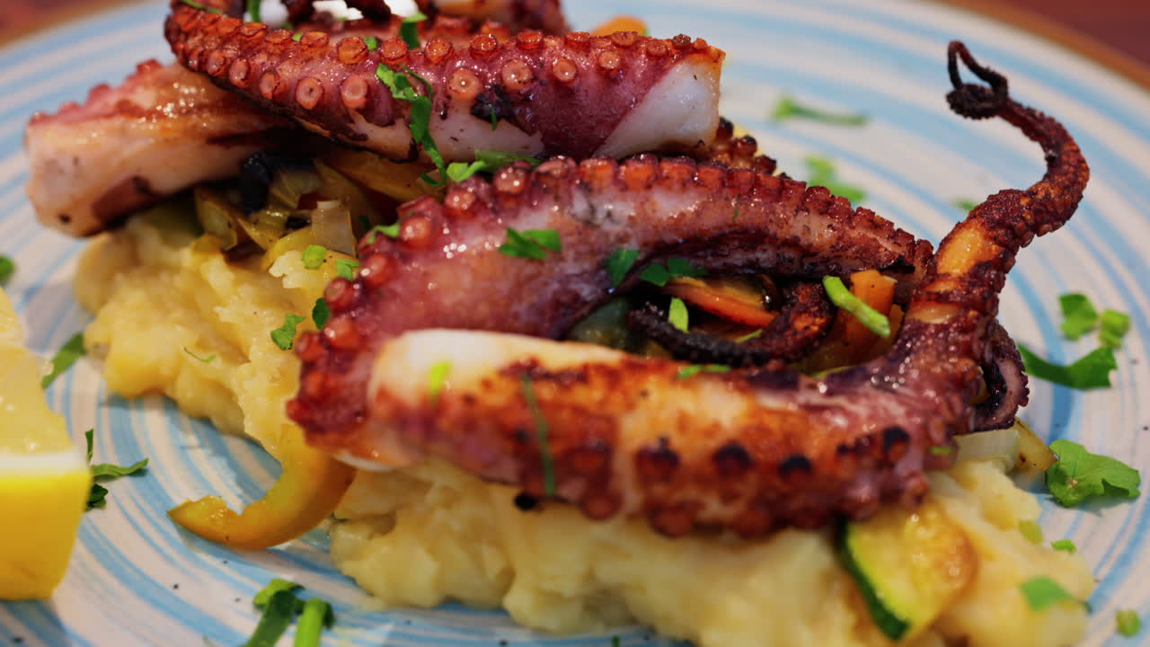 Close up of grilled octopus on a puree and a piece of lemon at a restaurant