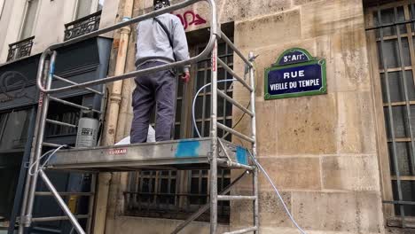 man working on scaffolding, renovating urban building.