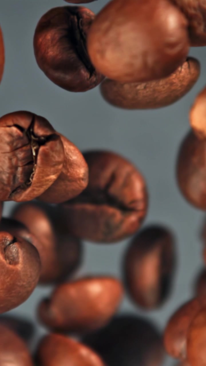 Chicchi di caffè tostati che cadono e si mettono a fuoco al rallentatore