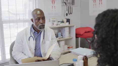 diverse male doctor and female patient talking in consulting room, slow motion