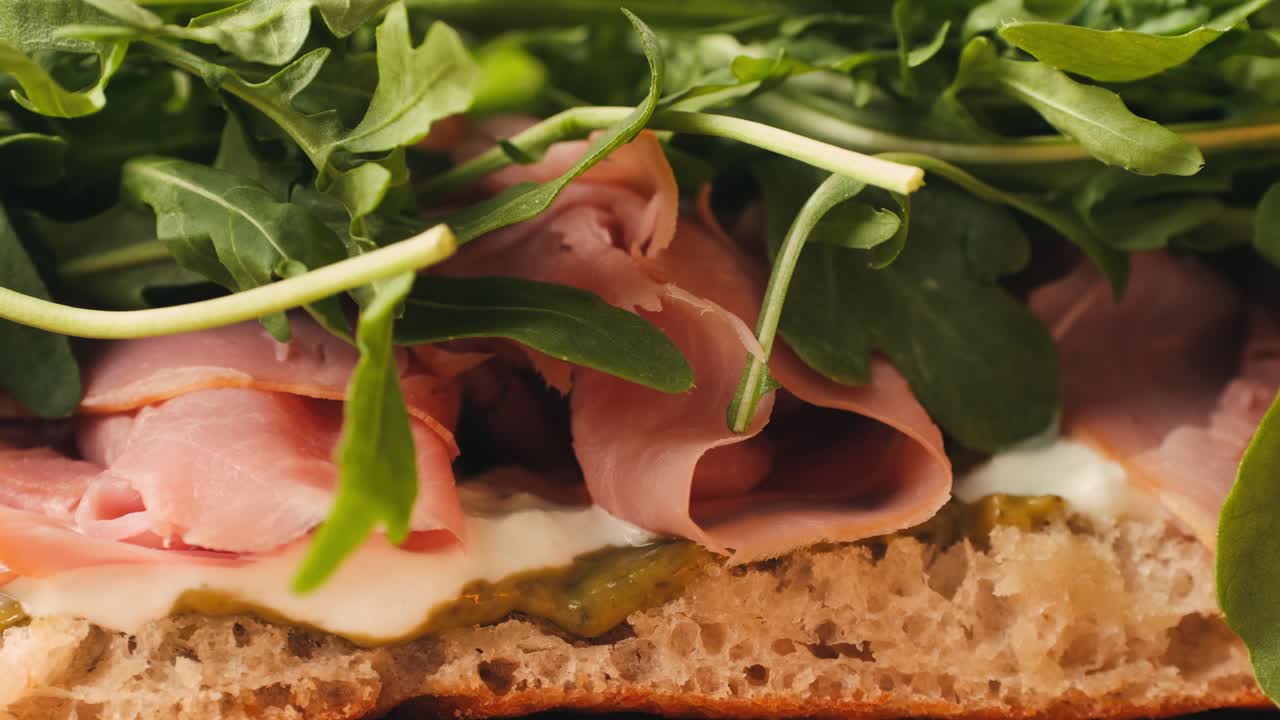Mortadella ham sandwich, Traditional italian focaccia filled with thin pesto slices of mortadella, served by chef man in cafe restaurant. Macro of traditional italian spanish tapas antipasti.