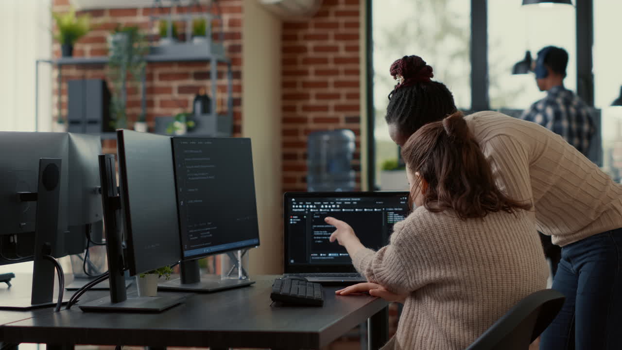 Two system engineers analyzing source code on laptop looking for errors on screen