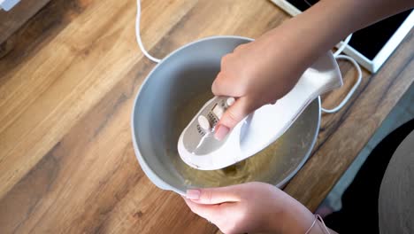 mujer usando una batidora eléctrica para preparar comida