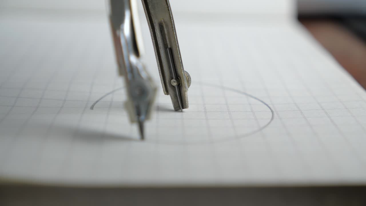 Macro of the compass drawing a circle on paper. Close up