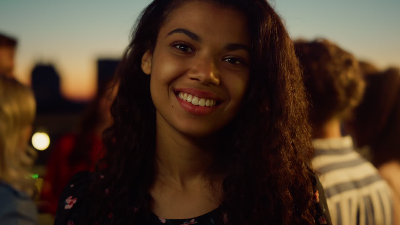 Portræt af afrikansk kvinde, der poserer for kameraet til fest. Afro-pige smiler udendørs.
