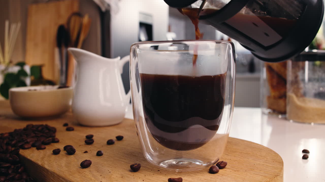 Servindo café fresco em uma xícara de vidro na cozinha