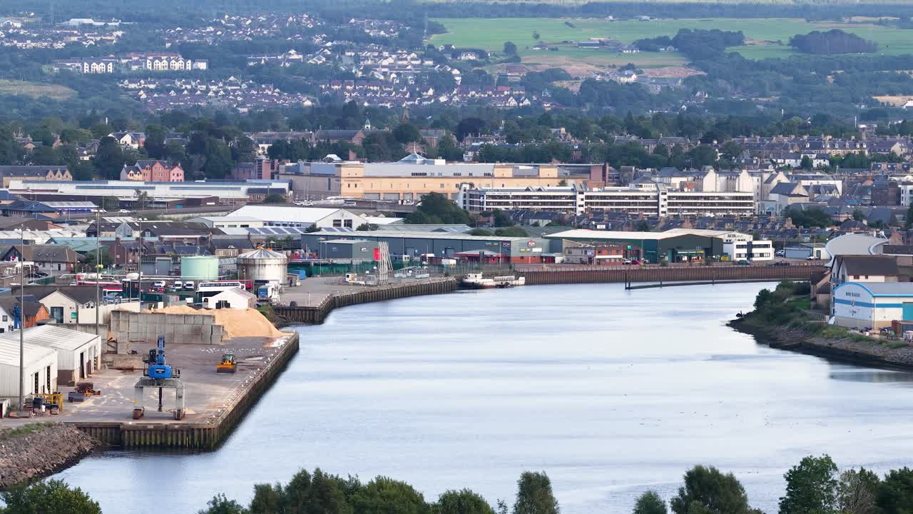 Aerial pan of Dundee’s riverfront, industrial port, urban landscape, and surrounding architecture in daylight