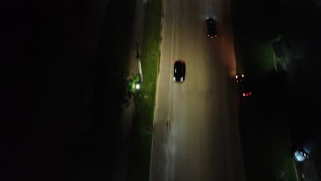 drone shot following cars on road at night with city lights