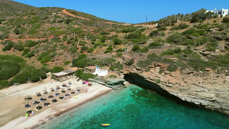 video aéreo de drones de la icónica playa de arena de andros con camas de sol y sombrillas, cícladas, grecia