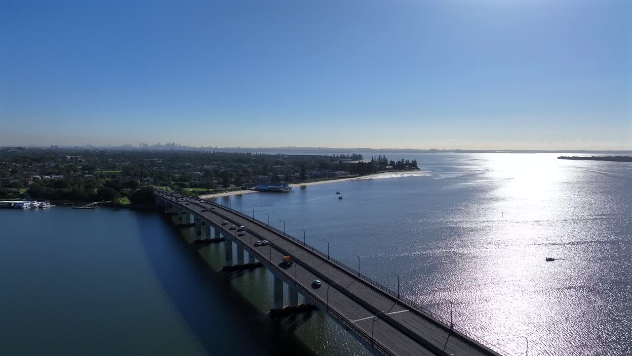 Droneoptagelse, der bevæger sig baglæns, mens biler kører over Captain Cook Bridge mod Sydneys indre forstæder, Australien.