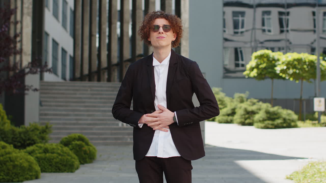 Sick businessman feels stomach pain standing on city street spasms gastritis or poisoning